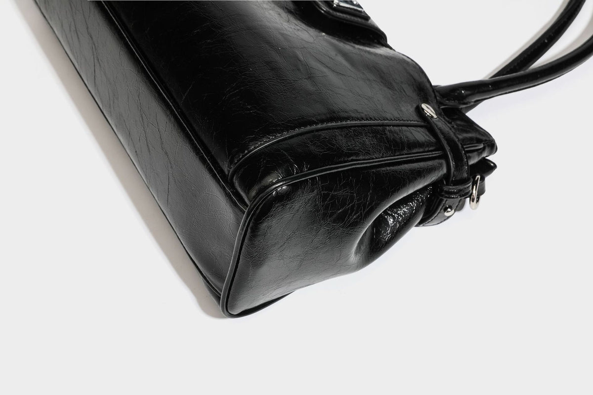 Structured glossy crinkled leather-look satchel with double top handles, front metal-plaque tab, silver-tone hardware, and
