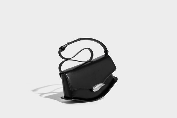 Small structured saddle bag with glossy leather-look finish, angular flap front, silver-tone metal clasp, and slim