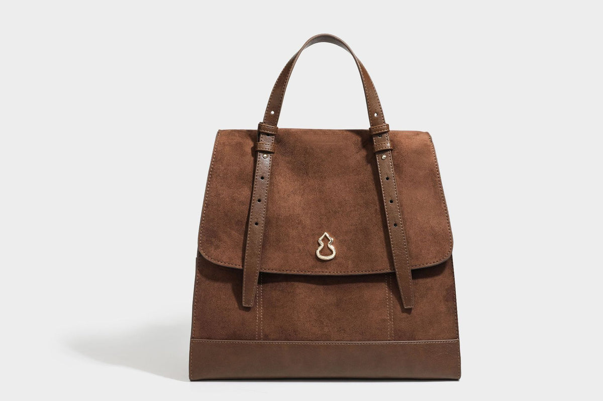 Structured suede-look convertible backpack handbag with flap closure and gold-tone emblem hardware in chocolate brown, detail