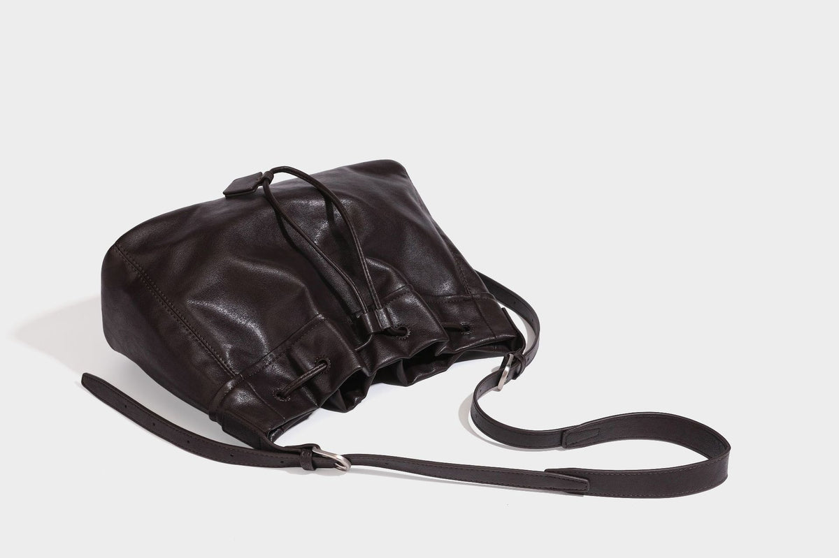Lässig fallende Beuteltasche mit Kordelzug in dunkler Espresso-Lederoptik, verstellbarem Riemen und Ringbeschlägen aus Metall