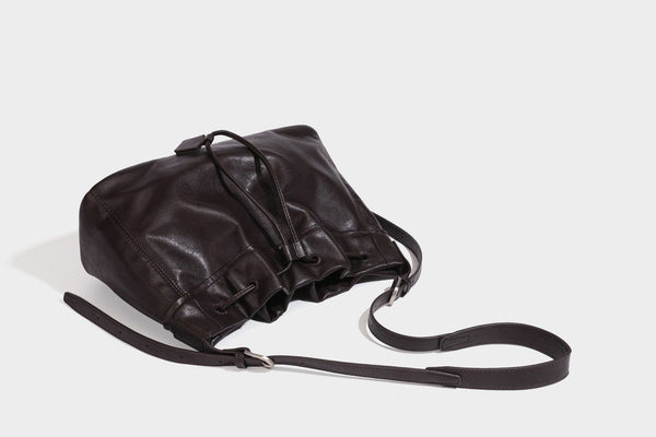 Lässig fallende Beuteltasche mit Kordelzug in dunkler Espresso-Lederoptik, verstellbarem Riemen und Ringbeschlägen aus Metall