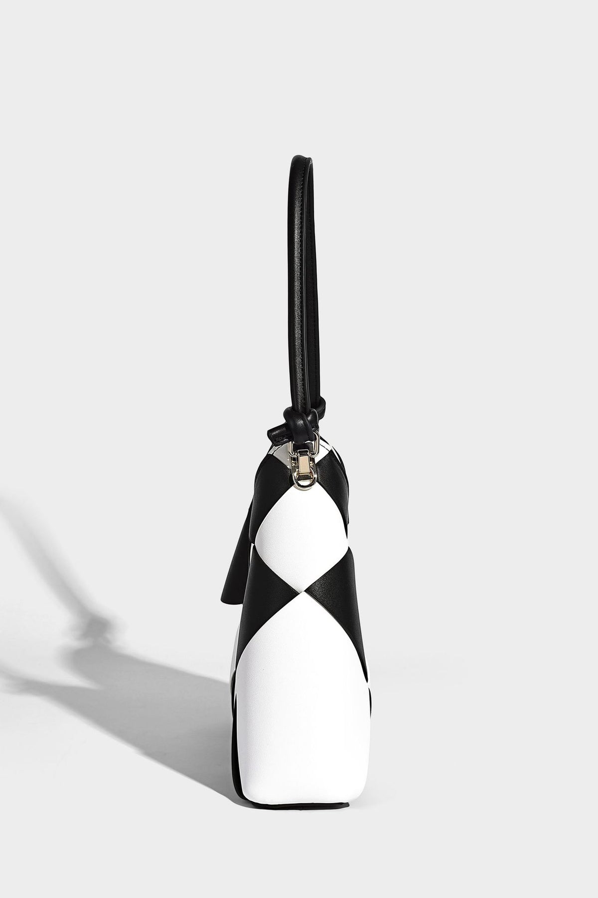 Compact bucket shoulder bag with black-and-white diamond patchwork panels, knotted top handle, gold-tone hardware, and