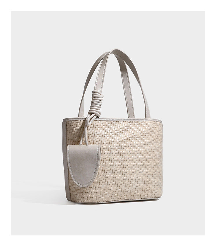 Strukturierte Tote Bag mit gewebter Oberfläche in Braun, goldfarbenen Metalldetails, seilumwickelten Tragegriffen, einer kleinen Fronttasche und weiteren Details