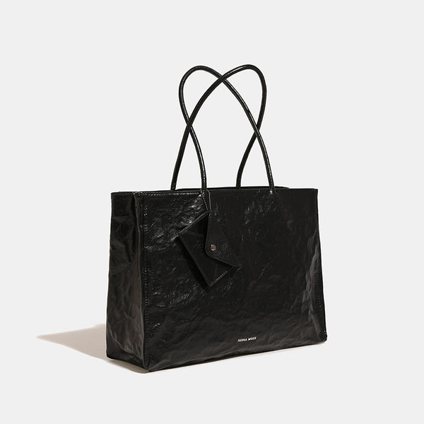 Large glossy crinkled rectangular tote bag with long double handles and hanging envelope snap tag, detail view 3