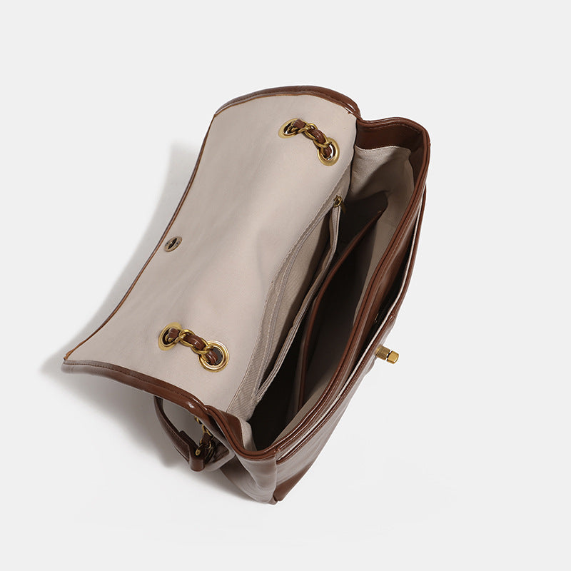 Structured flap shoulder bag with antique gold-tone chain strap and flower turn-lock clasp in crinkled leather-look finish