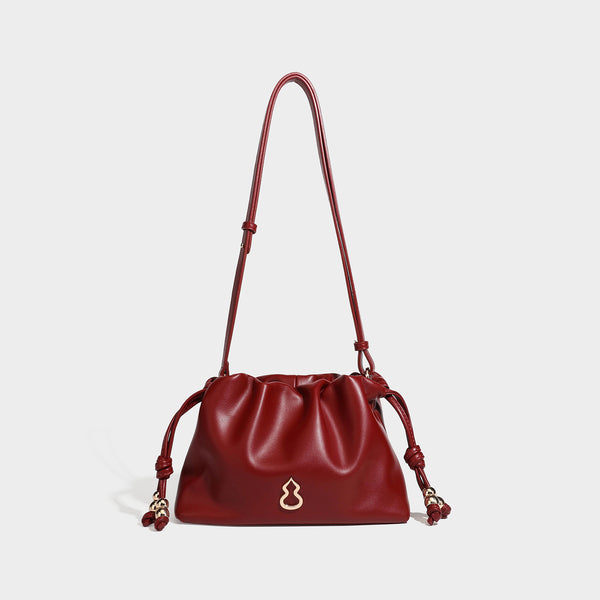 Slouchy ruched drawstring shoulder bag in smooth leather-look finish with gold-tone emblem and slim adjustable strap, detail