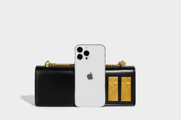 Structured rectangular crossbody bag with glossy finish, three vertical gold-tone embossed plaques, and gold chain strap