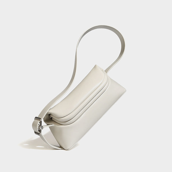 Compact structured baguette shoulder bag with smooth leather-look finish, zip top, and adjustable silver-buckle strap, detail