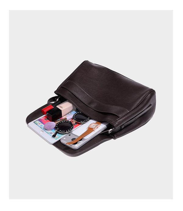 Strukturierte rechteckige dunkelbraune Schultertasche in Lederoptik mit Klappe, mehrlagigem Detail auf der Vorderseite und langem verstellbarem Riemen, Detailansicht