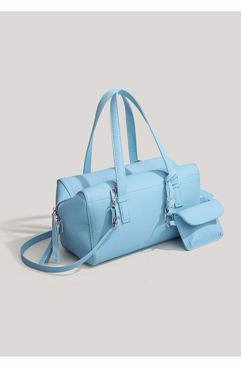 Light blue pebbled matte Boston tote bag with top handles, detachable shoulder strap, metal ring hardware, and matching mini