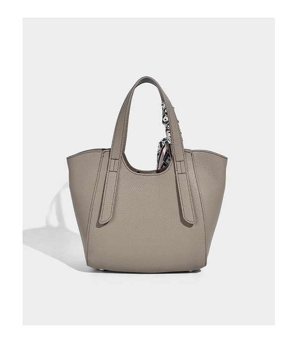 Structured pebbled leather-look tote bag with detachable scarf tie, dual top handles, and adjustable crossbody strap, detail