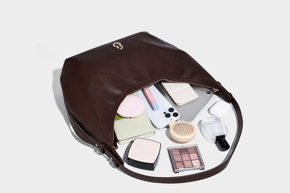 Lässig fallende, sichelförmige Hobo-Schultertasche in glatter dunkelbrauner Lederoptik mit Logo-Anhänger in Goldoptik und verstellbarem Schulterriemen