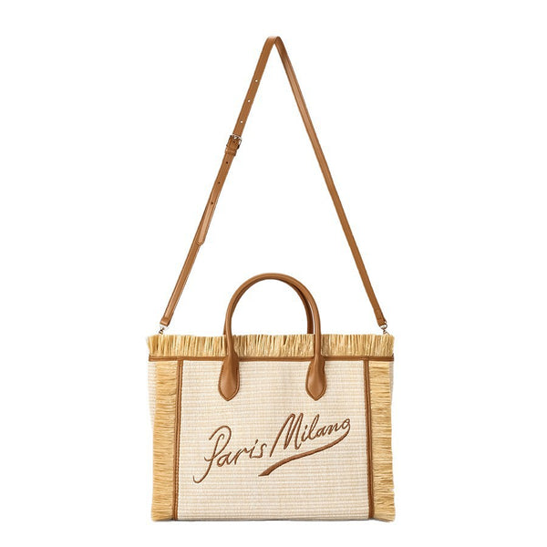 Naturfarbene, elfenbeinfarbene Strohtasche mit gewebter Optik, Bastfransenbesatz, cognacfarbenen Henkeln in Lederoptik und aufgesticktem Schriftzug „Paris Milano“