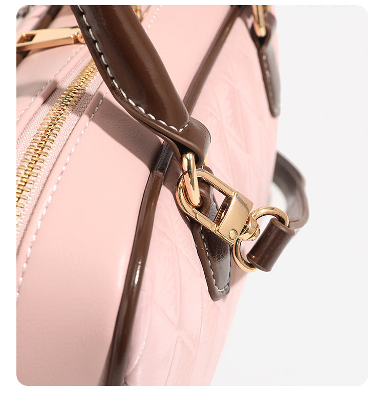 Blush pink quilted bowling barrel bag with dark brown leather-look trim and handles, baseball bat and ball charm, gold-tone