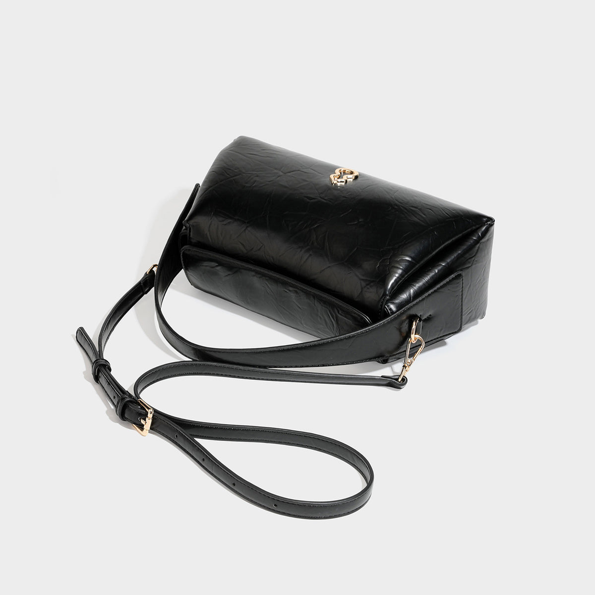 Glänzende, geknautschte trapezförmige Schultertasche mit Klappverschluss, goldfarbenen Logo-Details, Tragegriff und abnehmbarem, verstellbarem