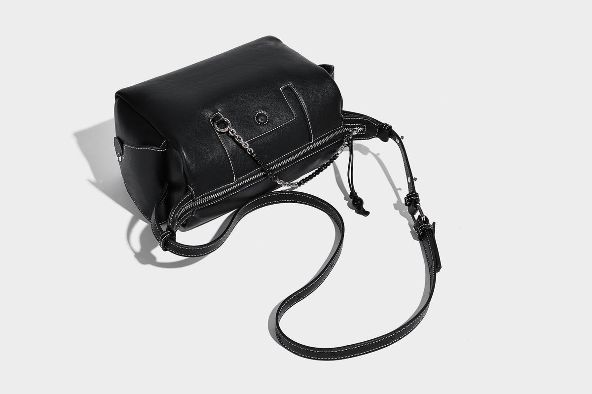 Small slouchy moto-style crossbody bag in smooth matte leather-look finish with white contrast stitching, silver-tone, detail