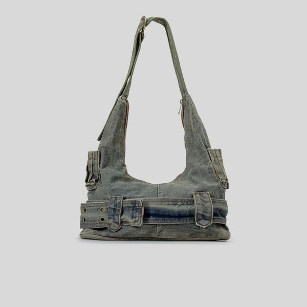Washed blue-gray denim slouchy hobo shoulder bag with wide grommeted belt panel, brass-tone D-ring buckle, exterior zip
