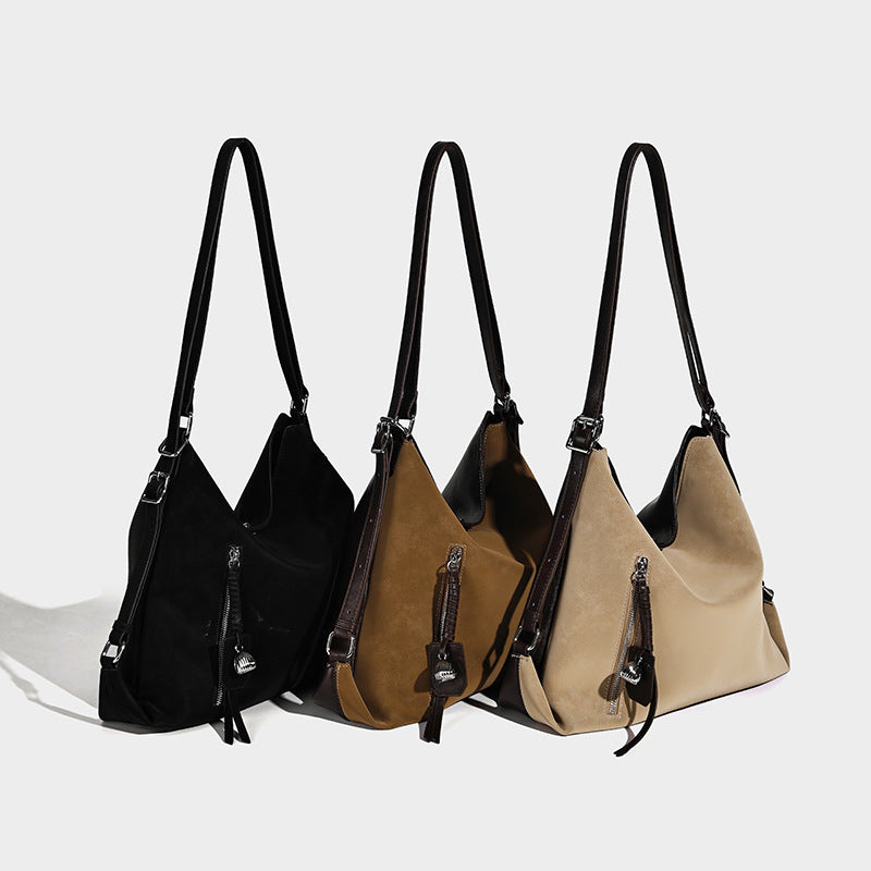 Slouchy hobo tote bag with matte leather-look finish, triangular silhouette, front zip pocket, and adjustable shoulder strap
