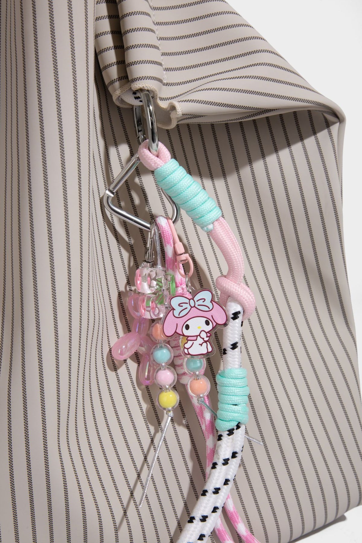 Slouchy pinstripe tote bag with braided rope handles, metal ring hardware, and colorful knotted rope charm, detail view 23