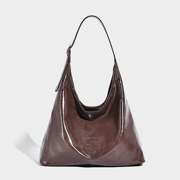 Glossy slouchy hobo shoulder bag with adjustable strap and embossed floral emblem, detail view 7