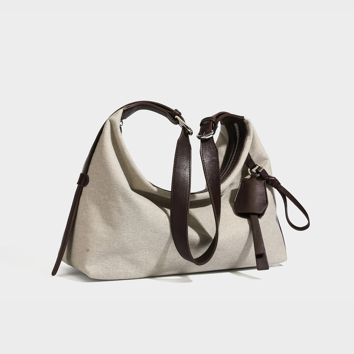 Weich fallende Hobo-Schultertasche aus haferfarbenem Canvas mit dunkelbraunem Besatz in Lederoptik, silberfarbenem Reißverschluss und langem, verstellbarem