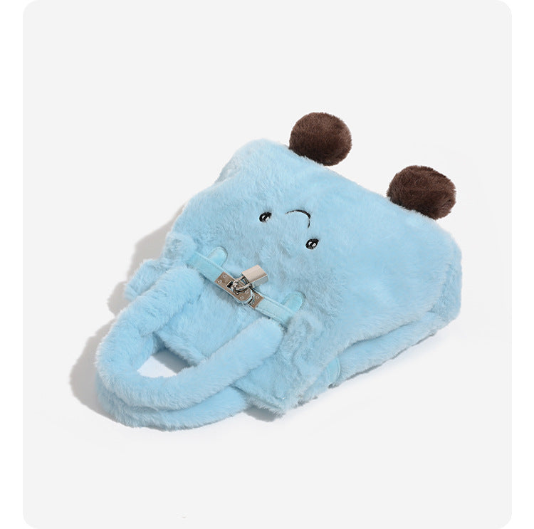 Ice-blue plush faux-fur Kelly-style convertible bag with embroidered smiling face, dark pom-pom feet, silver-tone clasp