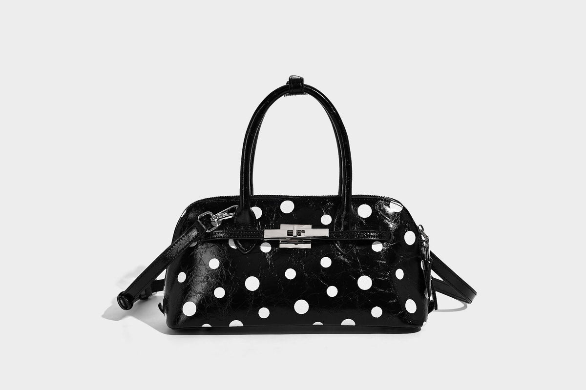 Glossy structured polka-dot satchel bag with dual top handles, silver turn-lock hardware, and detachable shoulder strap