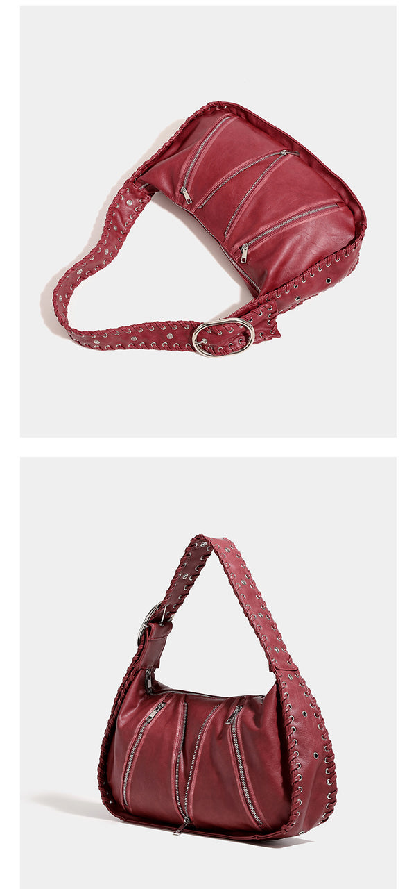 Slouchy hobo shoulder bag with wide braided eyelet strap, multiple front zip compartments, and silver-tone ring buckle