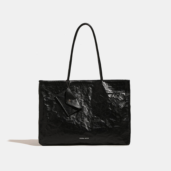 Large glossy crinkled rectangular tote bag with long double handles and hanging envelope snap tag, detail view 6