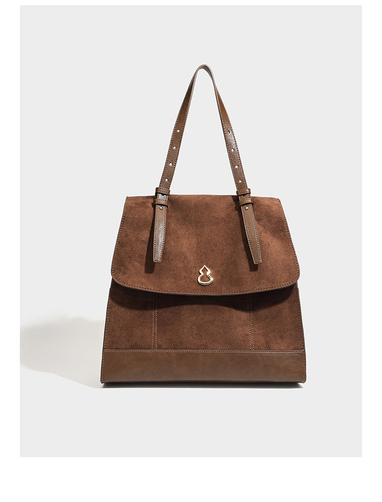 Structured suede-look convertible backpack handbag with flap closure and gold-tone emblem hardware in chocolate brown, detail