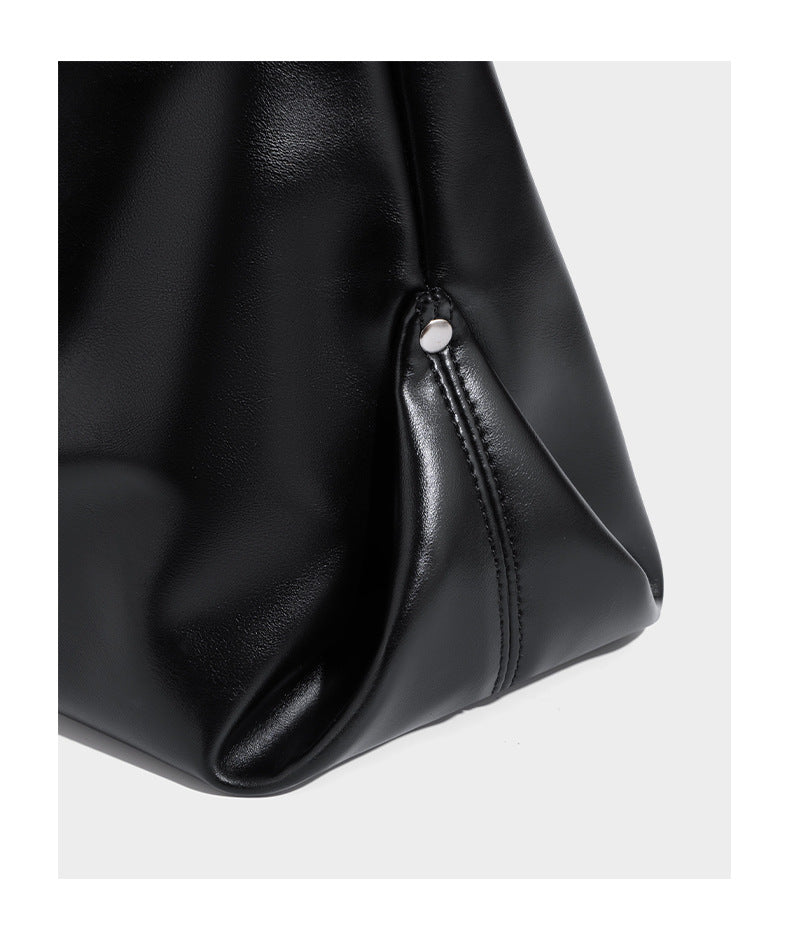 Große schwarze, weich fallende Hobo-Schultertasche in glänzender Lederoptik mit mit Ösen besetztem Riemen, silberfarbenen Metallbeschlägen und abnehmbarem