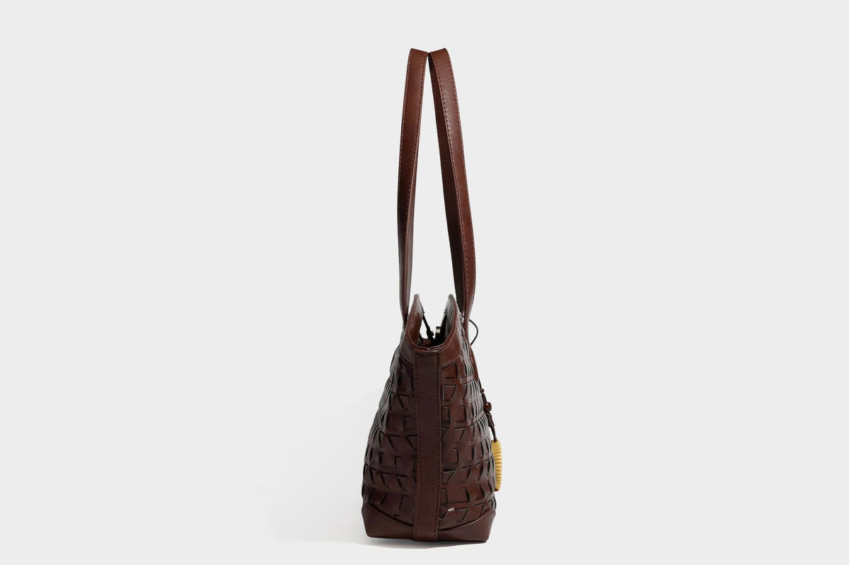 Large leather-look tote bag with geometric woven emboss, double shoulder straps, and round woven cord charm in brown, detail