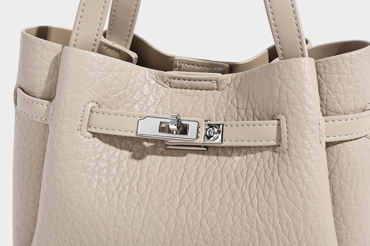 Small structured pebbled bucket tote with double top handles, silver turn-lock hardware, and detachable shoulder strap