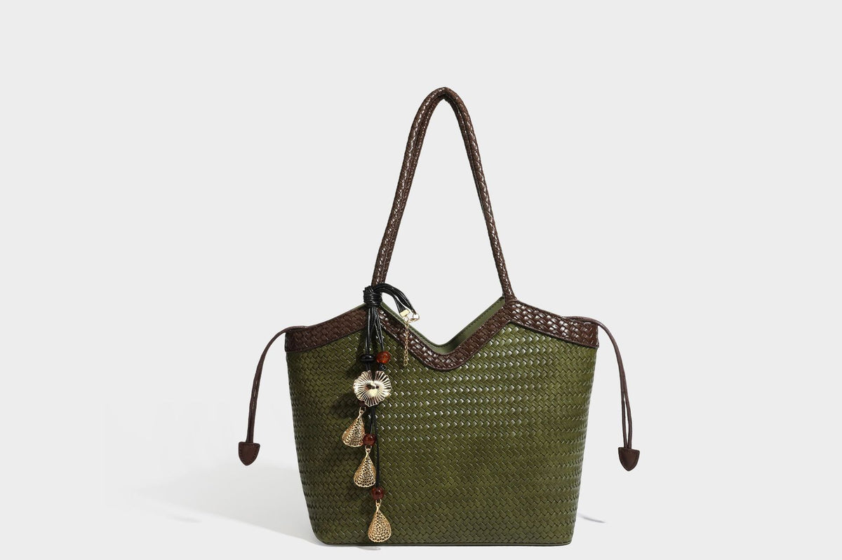 Olivgrüne Tote-Bag in Korbgeflecht-Optik mit dunkelbraunen geflochtenen Schulterriemen, seitlichen Kordelzügen und Perlenanhänger in Goldoptik
