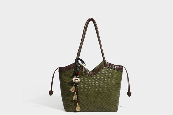 Olivgrüne Tote-Bag in Korbgeflecht-Optik mit dunkelbraunen geflochtenen Schulterriemen, seitlichen Kordelzügen und Perlenanhänger in Goldoptik