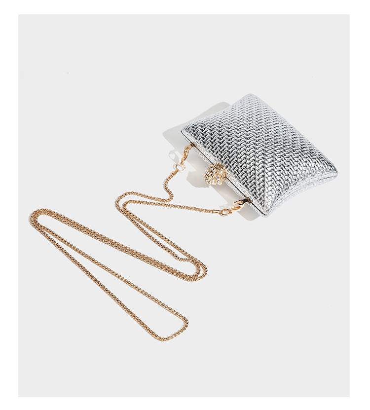 Small structured rectangular metallic woven-texture clutch bag with jeweled knob clasp and gold-tone chain strap, detail view