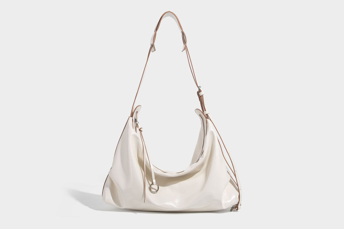 Glossy black slouchy hobo shoulder bag with zip closure, silver-tone ring hardware, and adjustable crossbody strap, detail