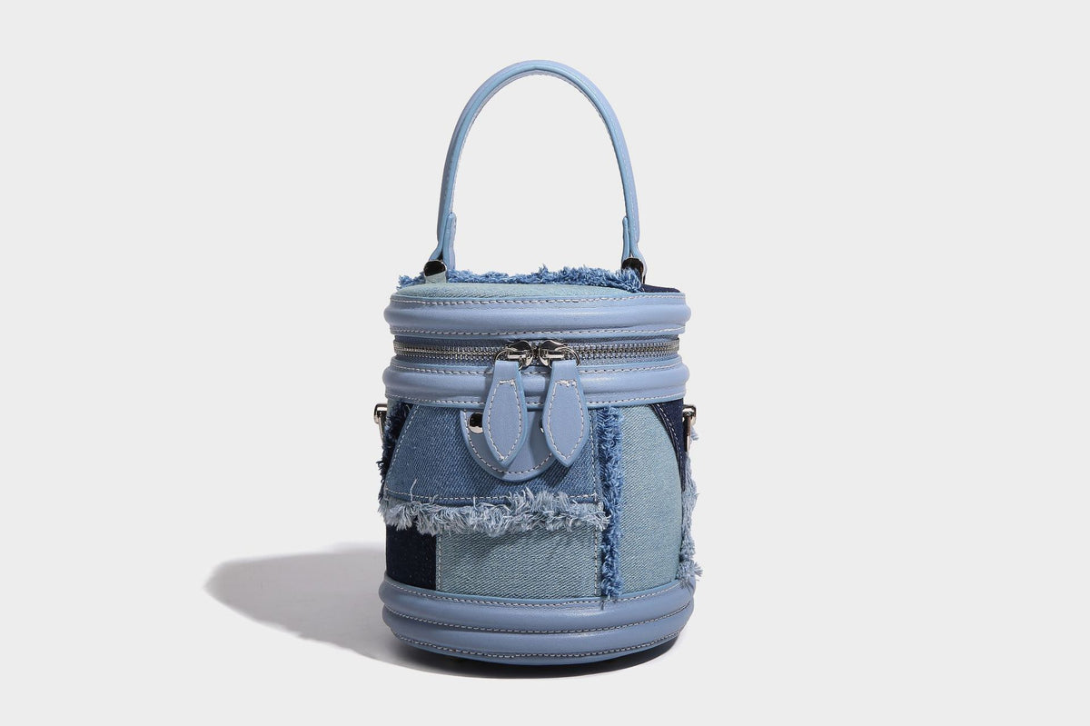 Mini cylindrical barrel bucket bag in denim patchwork with frayed edges, smooth leather-look trim, zip-around top closure
