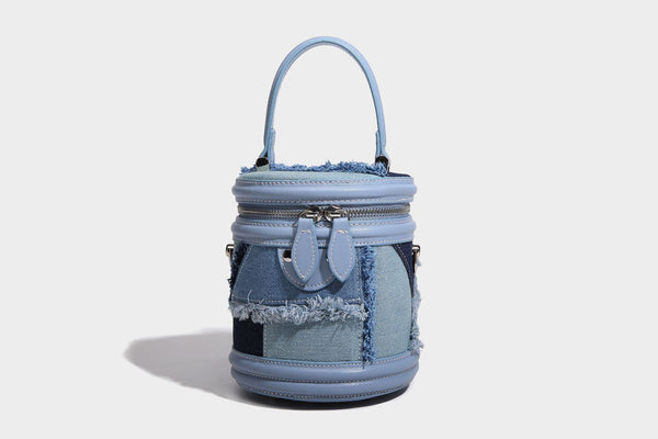 Mini cylindrical barrel bucket bag in denim patchwork with frayed edges, smooth leather-look trim, zip-around top closure