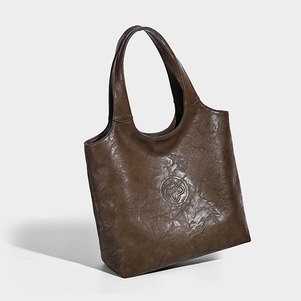 Large open-top tote bag with crinkled leather-look finish, long double shoulder straps, and embossed circular detail on