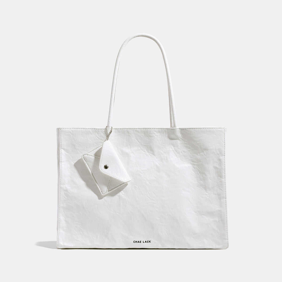 Structured rectangular crinkle leather-look tote bag with long rounded handles, zip top, and envelope-style hanging tag
