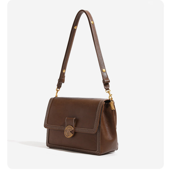 Structured flap shoulder bag with gold-tone circular turn-lock closure, white contrast stitching, and adjustable strap