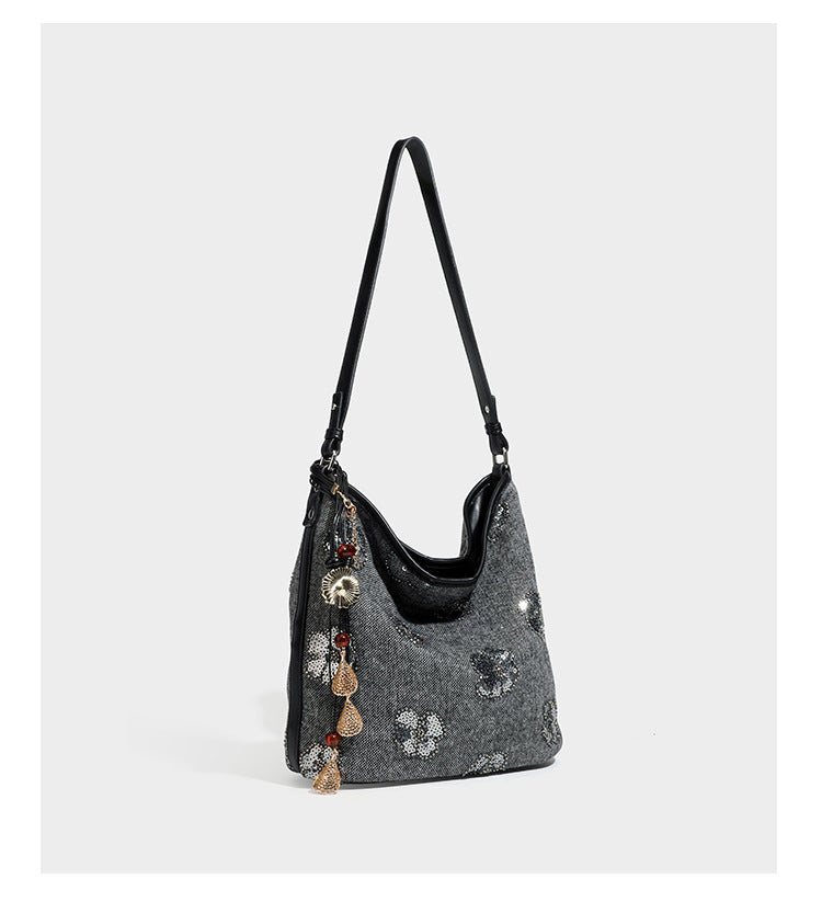 Lässig fallende Hobo-Schultertasche aus anthrazitfarbenem Webstoff mit floraler Stickerei aus silberfarbenen Pailletten, schwarzem Besatz in Lederoptik und langem