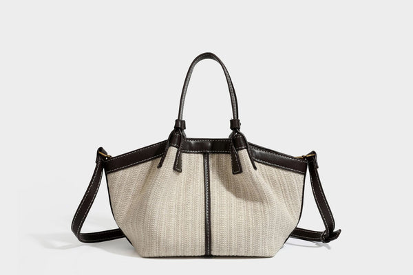 Cremefarbene geflochtene Tote-Bag mit dunkelbraunen Besätzen in Lederoptik, kontrastierenden weißen Nähten, zwei oberen Henkeln und abnehmbarem Schulter