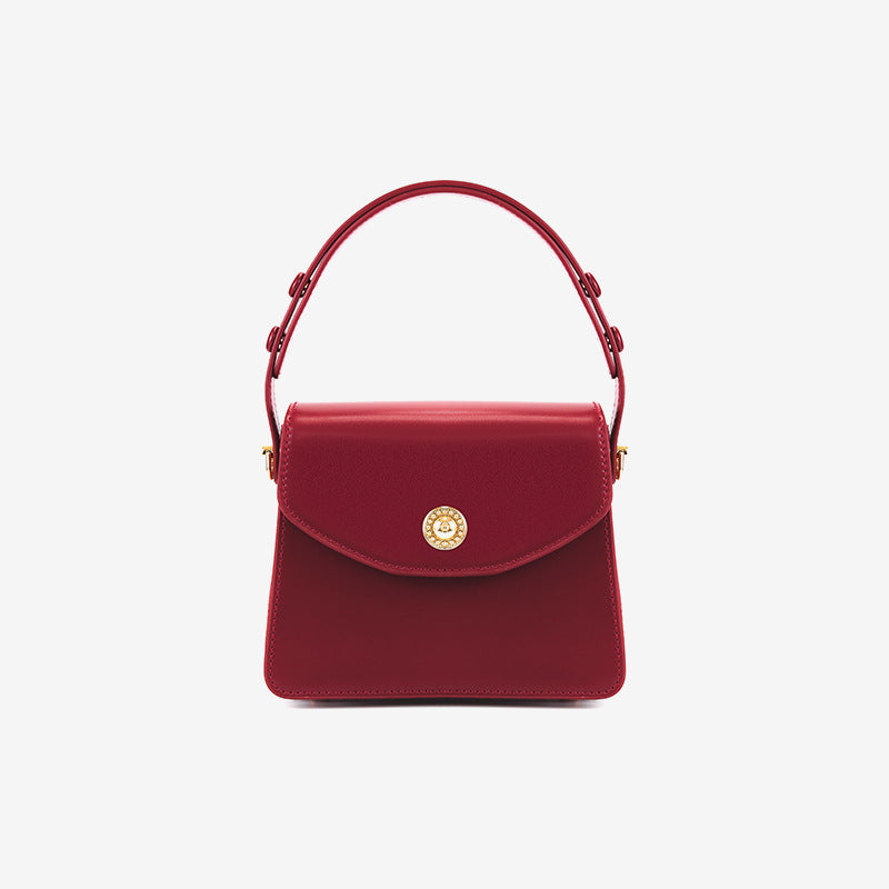 Kleine strukturierte Henkeltasche mit Überschlag in tiefem Rot, glatter Lederoptik, goldfarbenem Drehverschluss, kurzem Henkel und