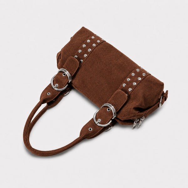Weiche, matte Schultertasche in Zylinderform aus Veloursleder-Optik mit silberfarbenem Nietenbesatz, Ringschnallen-Details und zwei gerollten Tragegriffen, Detailansicht