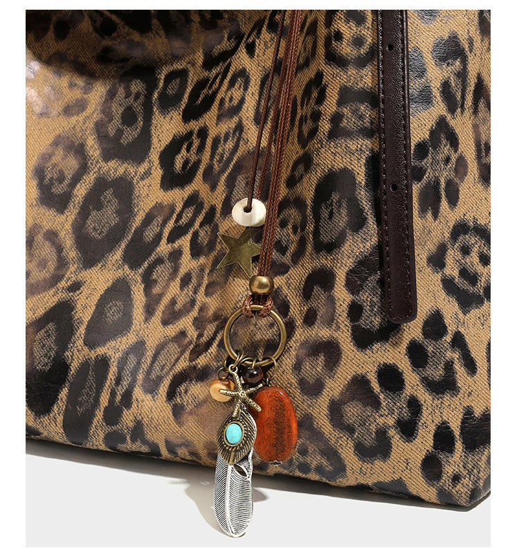 Slouchy leopard-print shoulder tote bag in tan and brown with long double straps, side tie straps, and dangling charm, detail