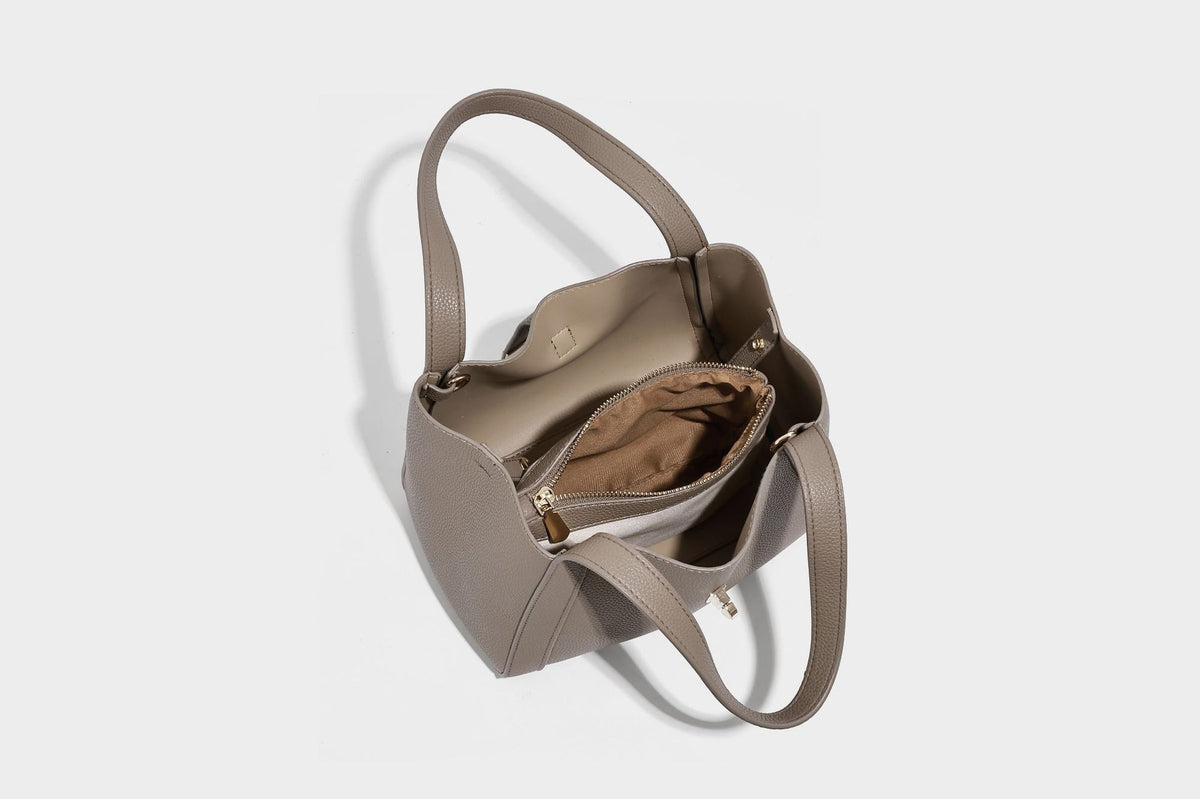 Structured trapezoid tote bag in taupe pebbled leather-look finish with gold-tone turn-lock hardware, dual top handles, and