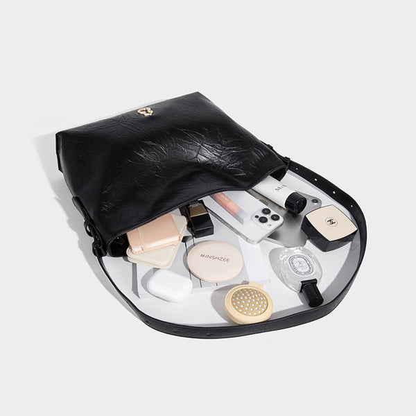 Large slouchy hobo shoulder bag in glossy crinkle leather-look finish with gold-tone emblem hardware and adjustable strap