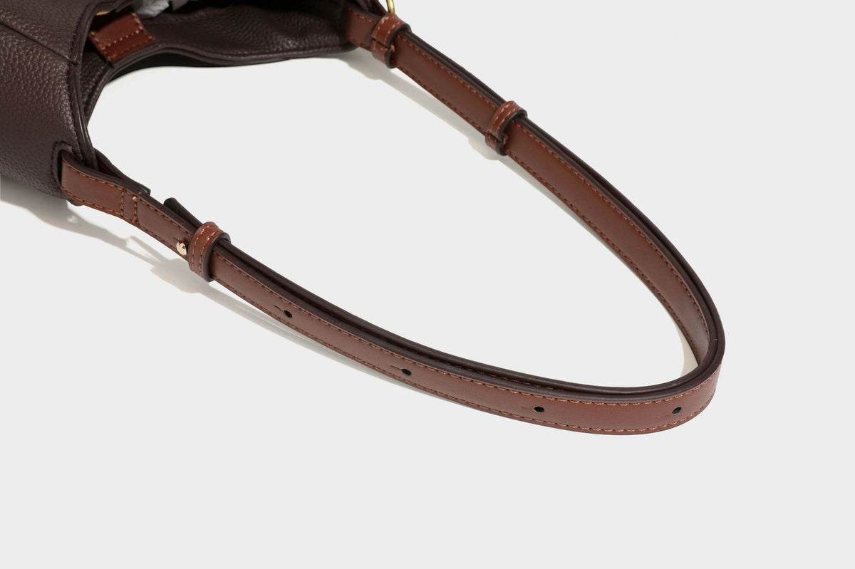 Hobo-Schultertasche in dunklem Espresso mit genarbter Oberfläche, warmen cognacfarbenen Details, verstellbarem schmalem Riemen, goldfarbenen Ringbeschlägen und geknotetem